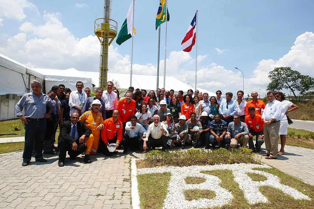Grupo de trabalhadores e autoridades posa diante de mastros com as bandeiras do Brasil e da Bahia, em área da usina de biodiesel da Petrobras em Candeias