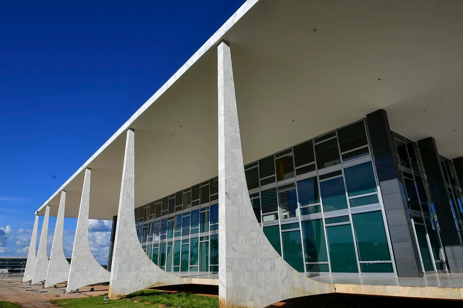 Fachada do edifício do Supremo Tribunal Federal em Brasília, com grandes colunas de mármore e janelas de vidro sob céu azul
