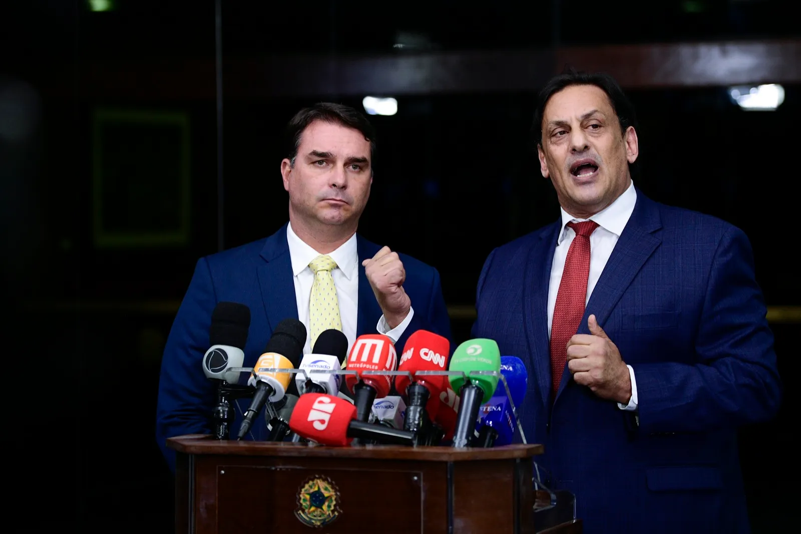 Flávio Bolsonaro e seu advogado Frederick Wassef dão entrevista diante de microfones no Senado