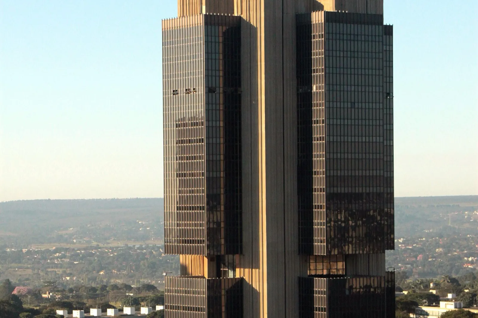 Parte da torre de concreto e vidro escuro da sede do Banco Central do Brasil, em Brasília, sob céu azul